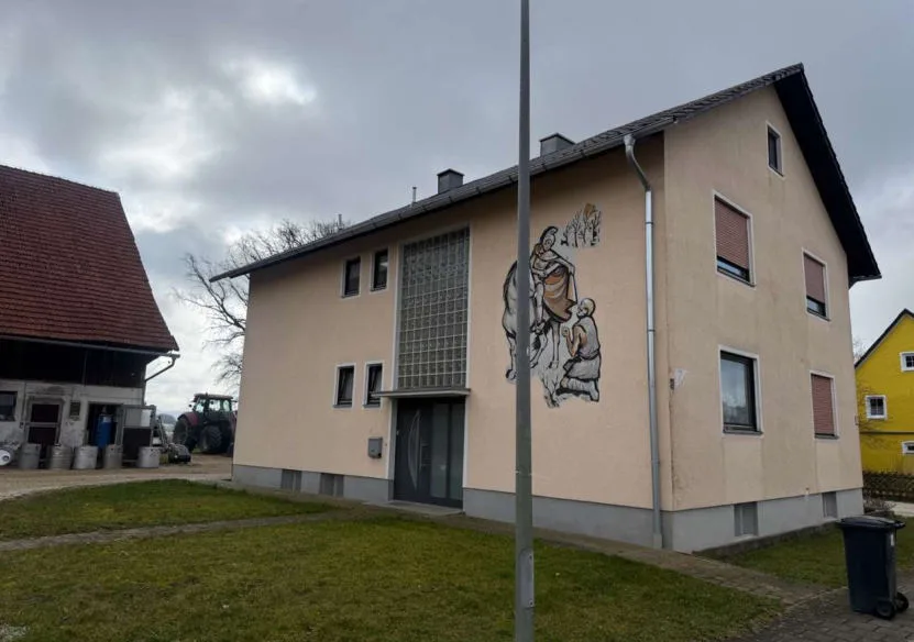 Außenansicht Wohnhaus mit Wandmalerei, daneben Hofgebäude