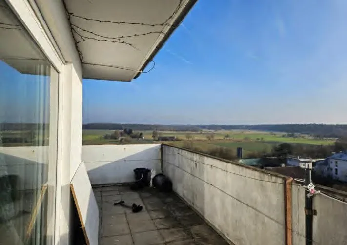 Blick vom Balkon in eine weite Landschaft mit Feldern und Waldrand; Gebäude nicht als Hauptmotiv sichtbar.