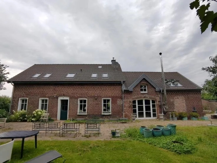 Frontale Rückansicht eines zweigeschossigen Backsteinhauses mit Dachflächenfenstern, Terrasse und Garten.