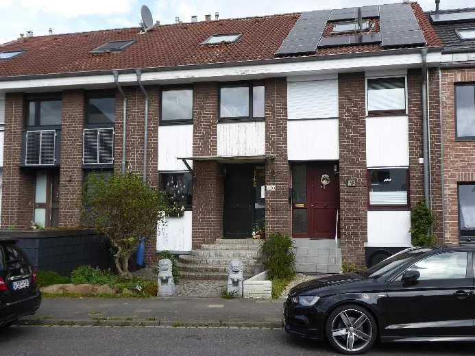 Straßenansicht des Reihenhauses mit Klinkerfassade, Dachflächen und parkendem Pkw