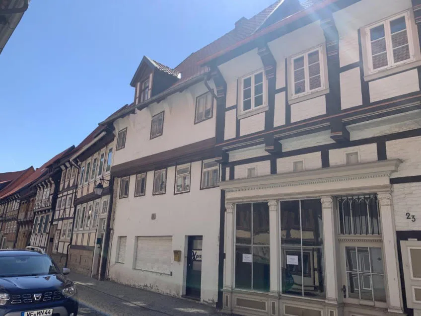 Straßenansicht der Fassade mit weiß verputztem Mittelhaus und Ladenfront