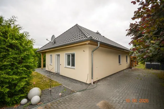 Schräge Seitenansicht des eingeschossigen Hauses mit Pflasterzufahrt und Eingangsbereich