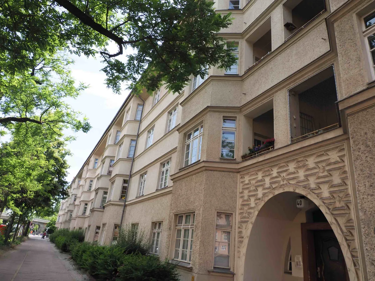 Straßenansicht der Gebäudefassade mit Torbogen und Hausnummer 40, teilweise von Laub verdeckt