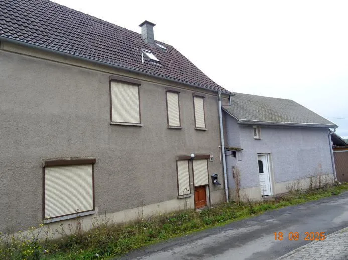 Straßenseitige Außenansicht eines Wohnhauses mit Satteldach, Rollläden und angebautem Nebengebäude.