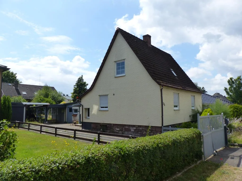 Außenansicht eines freistehenden Einfamilienhauses mit hellen Klinkerwänden und dunklem Satteldach, schräg von der Seite aufgenommen