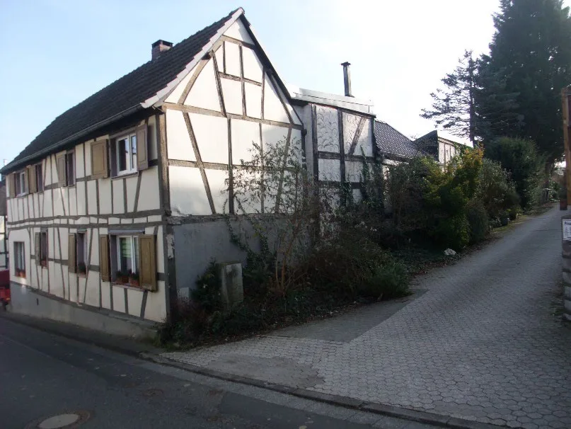 Straßenseite eines Fachwerkhauses mit Pflasterzufahrt, Gebäude gut sichtbar, Seitenansicht.