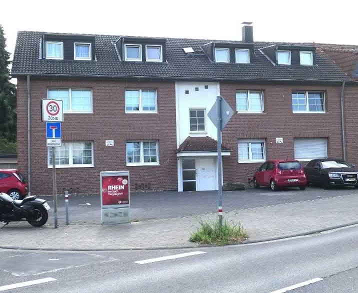 Frontansicht des dreigeschossigen Mehrfamilienhauses mit Klinkerfassade und Dachgauben von der Straße aus