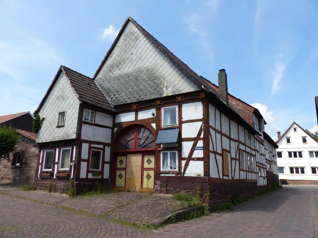 Außenansicht eines denkmalartigen Fachwerkhauses mit Schieferfassade an einer Ecke, unverstellt aufgenommen.
