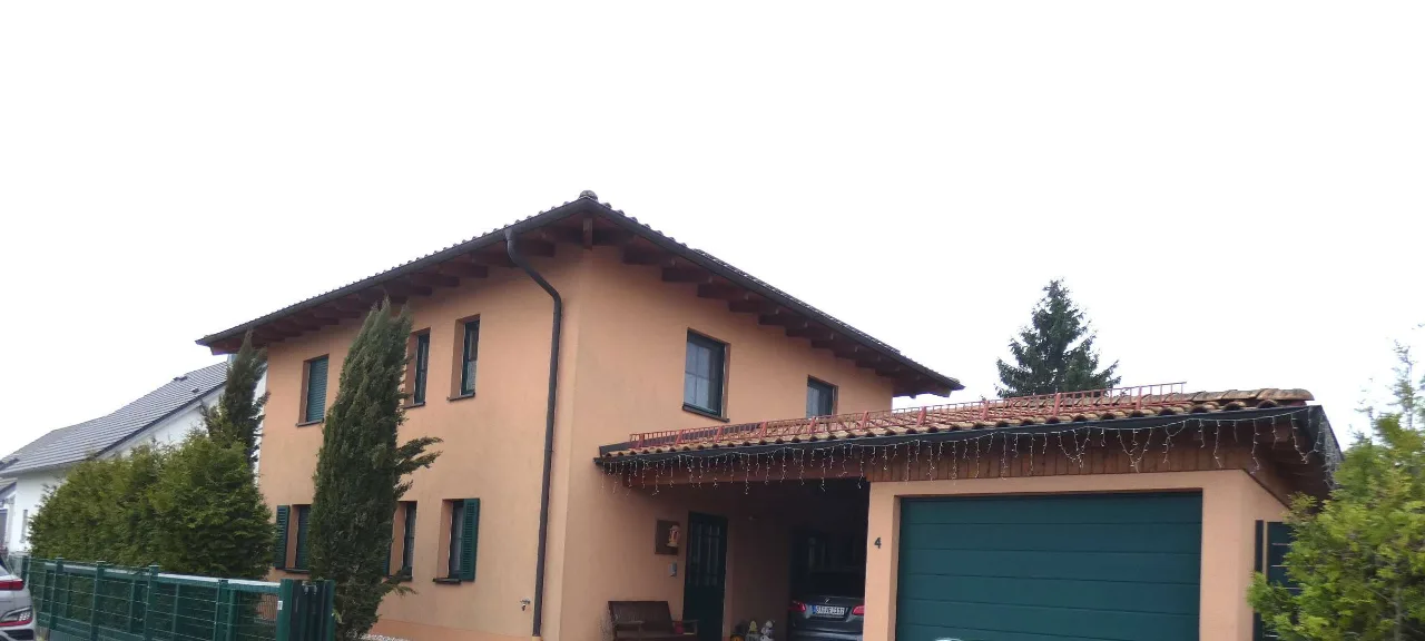 Außenansicht des Wohnhauses mit Carport und grünem Garagentor, von der Straßenseite aufgenommen