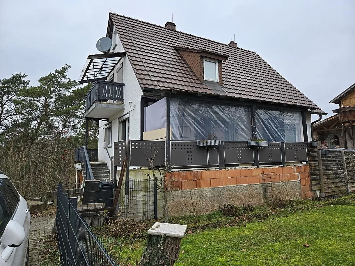 Wohnhaus mit Satteldach, Balkon und Glasvordach, schräge Ansicht von der Gartenseite, unverstellt.