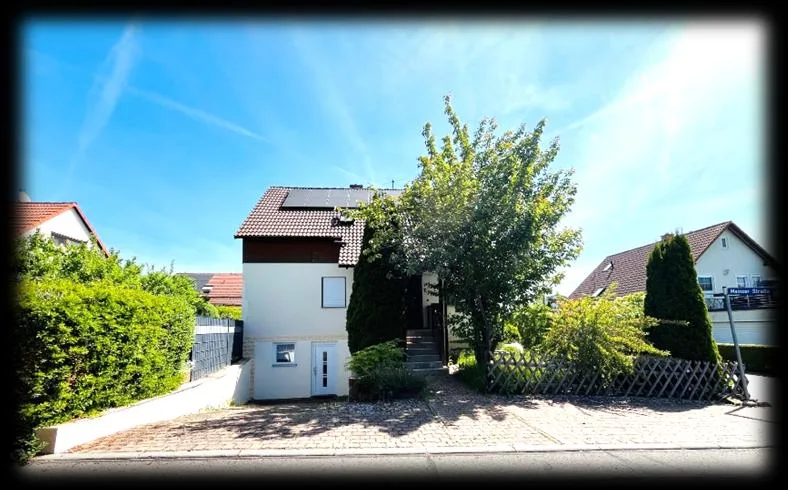 Freistehendes Wohnhaus mit Satteldach und Solaranlage, Vorderansicht mit Vorgarten und Zugang.