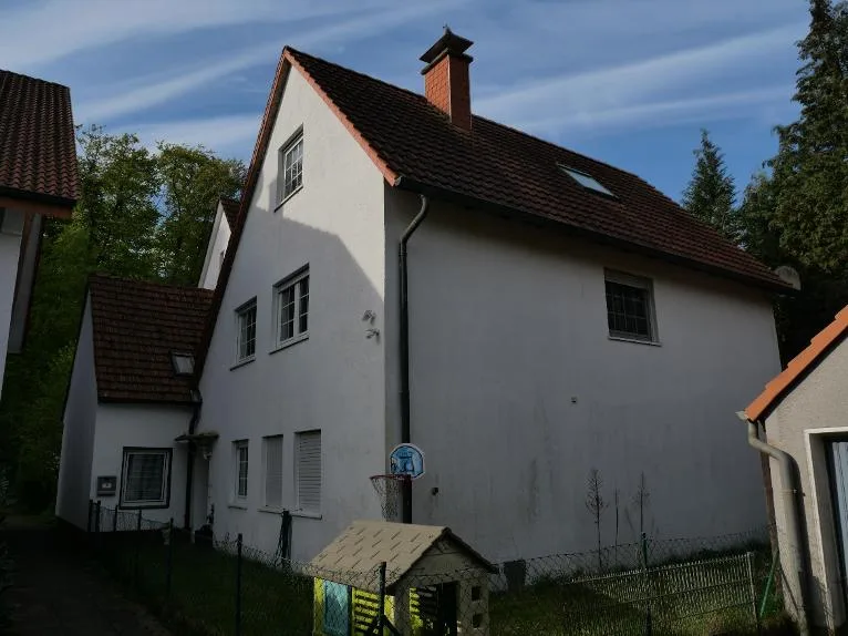 Außenansicht des Wohnhauses mit Satteldach, Schornstein und Fensterfronten.
