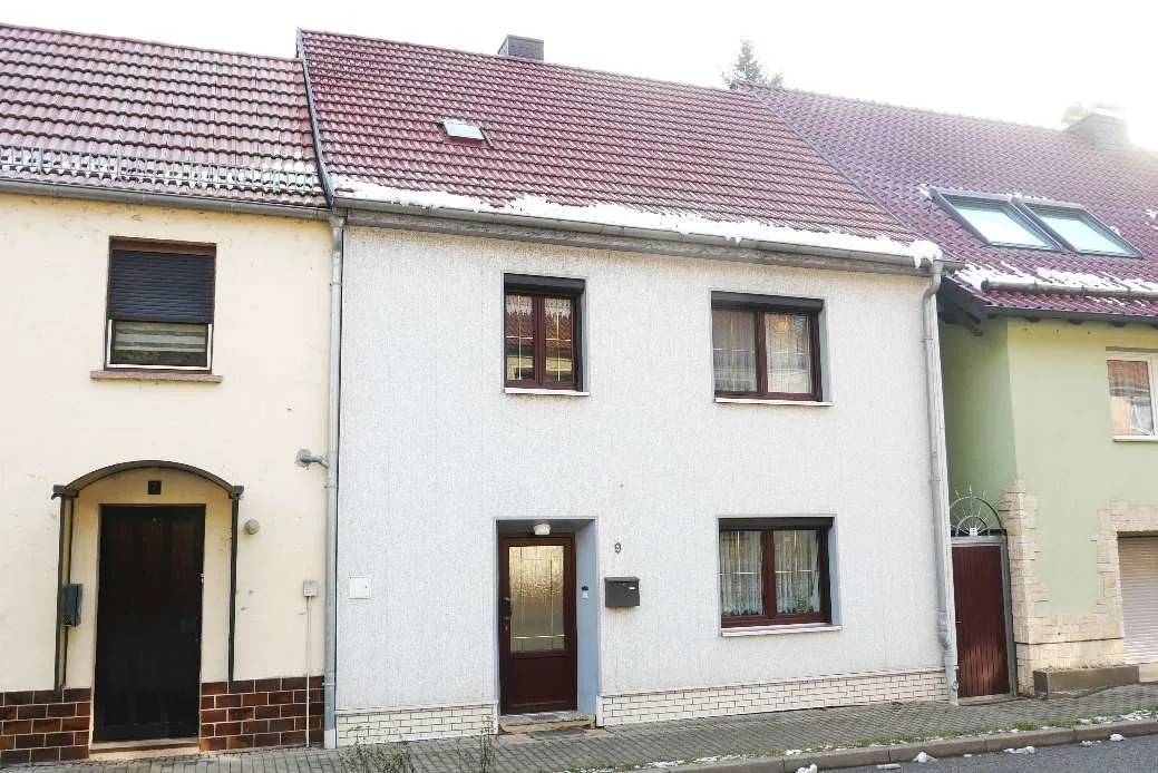 Front facade of residential building with main entrance, showing white rendered walls and red tile roof