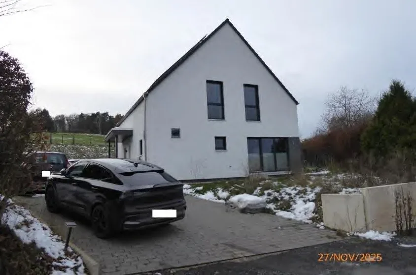 Moderne Frontansicht des weißen Einfamilienhauses mit Garage und gepflasterter Einfahrt