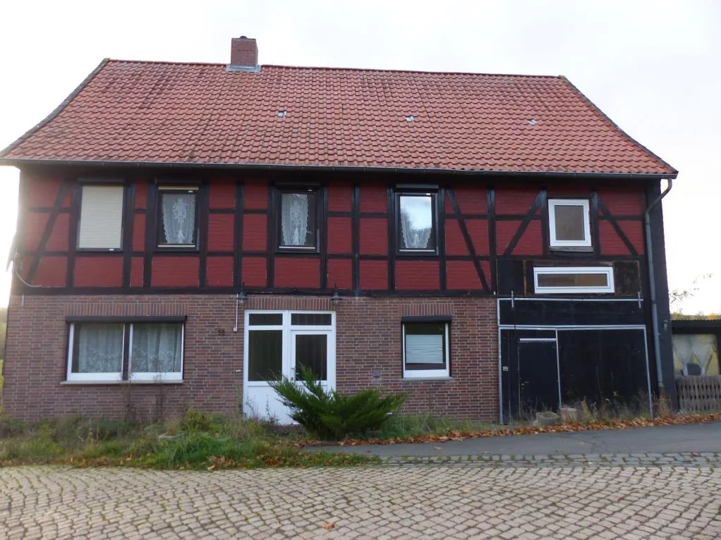 Frontansicht eines Fachwerkhauses mit Ziegeldach, Backsteinfassade und mehreren Fenstern