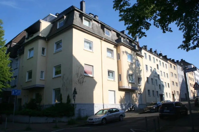 Außenansicht des Mehrfamilienhauses mit Eckbebauung, Erkern und Dachgeschoss bei Sonnenlicht.