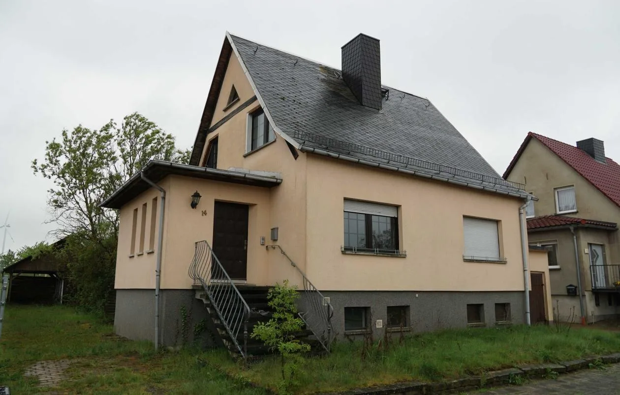 Frontansicht eines freistehenden Einfamilienhauses mit Satteldach und Eingangstreppe