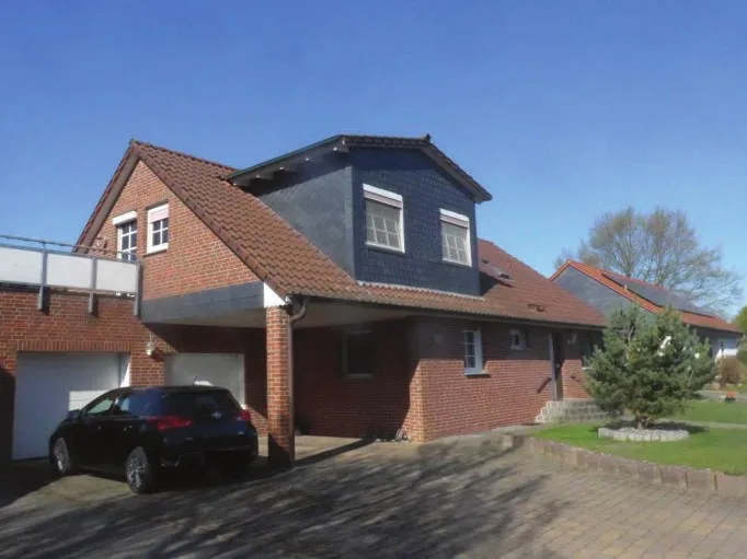 Außenansicht eines klinkerverblendeten Einfamilienhauses mit Garage und Carport