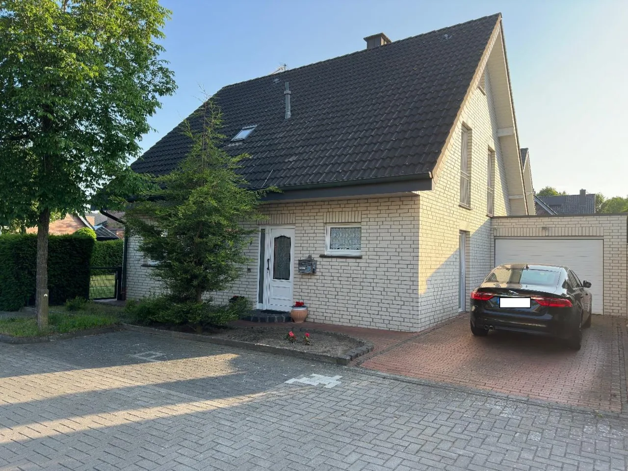 Einfamilienhaus mit Garage, schräge Frontansicht, davor parkendes dunkles Fahrzeug.