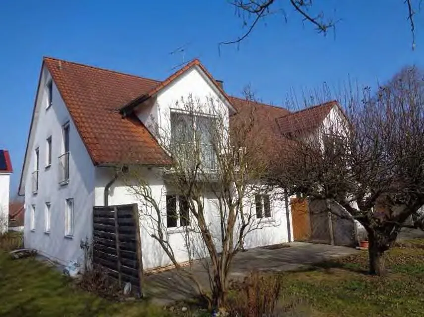 Außenansicht des Einfamilienhauses mit Satteldach und weißer Fassade, Vorgarten und Carport