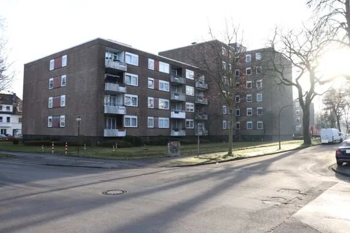 Schräge Außenansicht eines viergeschossigen Wohnblocks mit Balkonen und Fenstern, klar und gut ausgeleuchtet.