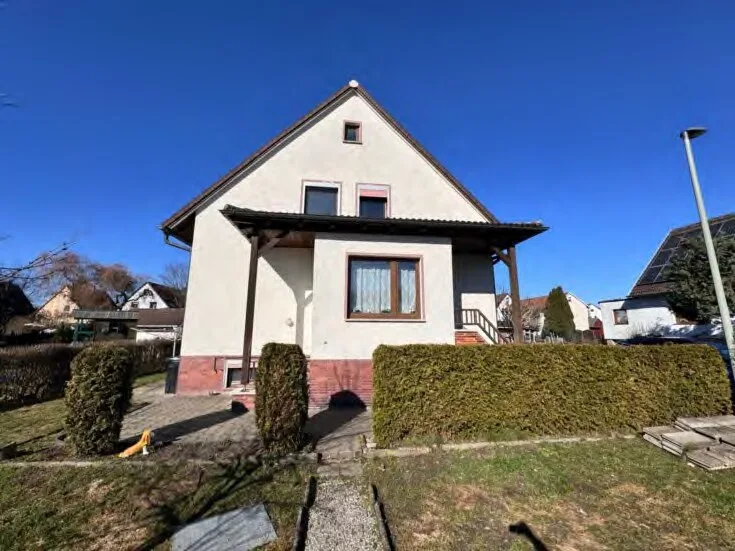 Außenansicht des Wohnhauses mit Satteldach, Vordach und Eingangsbereich bei Sonnenschein.