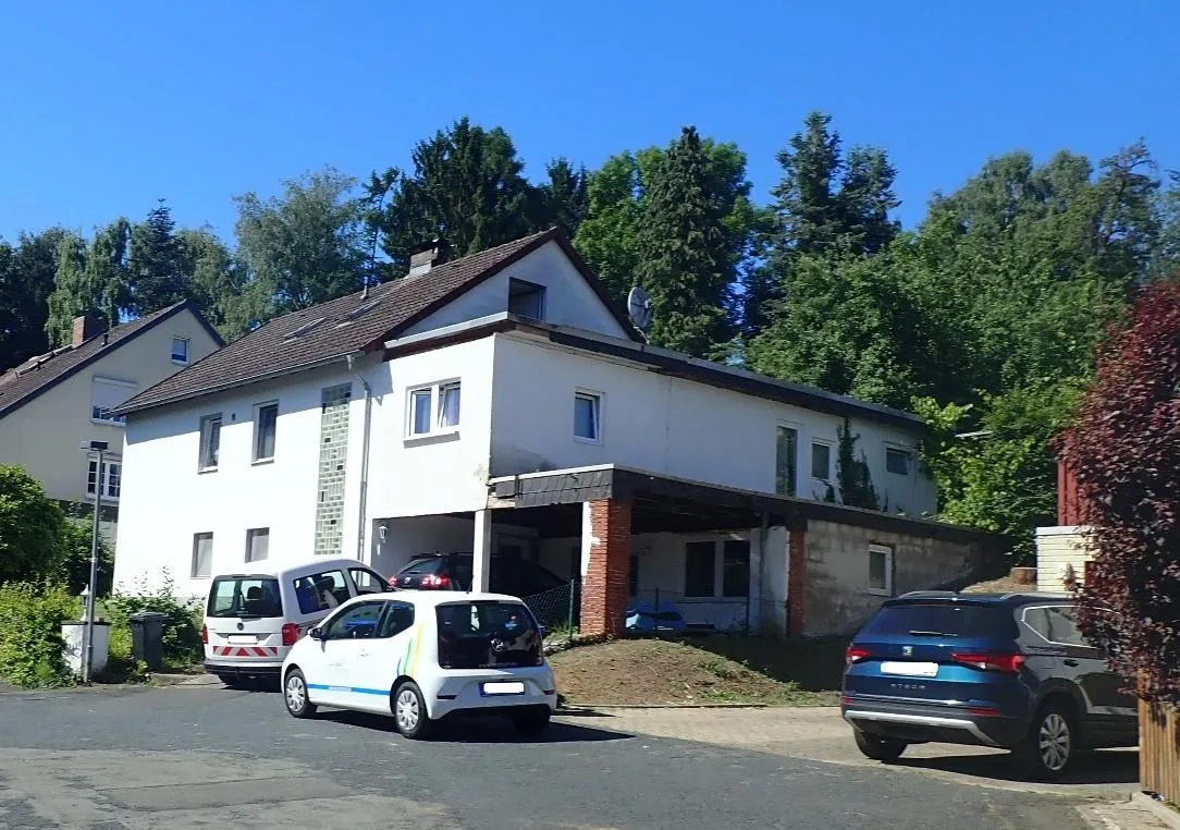 Frontansicht des Einfamilienhauses mit Carport und geparkten Fahrzeugen