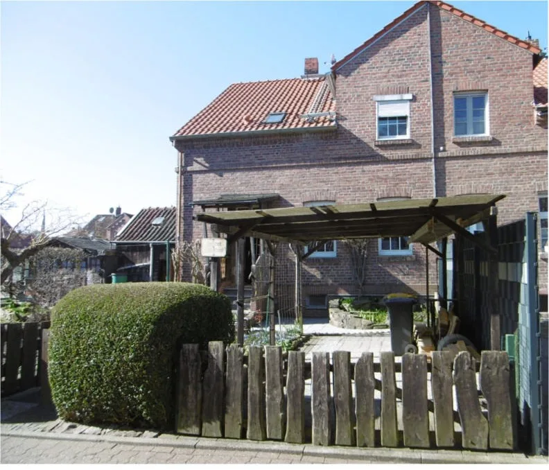 Klinkerhaus mit Satteldach, Carport und Holzzaun vor dem Grundstück, von der Straße aus fotografiert.