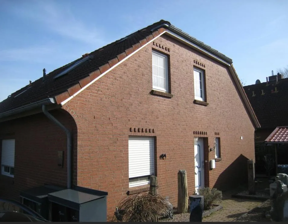 Giebelseitige Außenansicht des Klinker-Wohnhauses mit Satteldach bei Sonnenschein