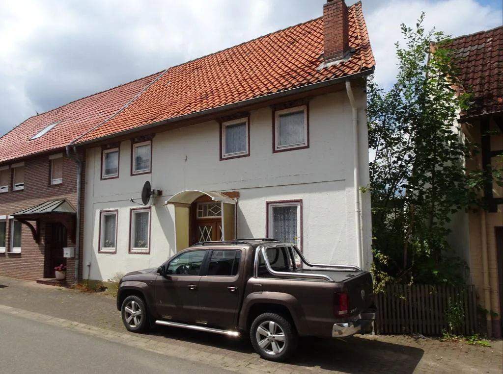 Wohnhaus mit rotem Ziegeldach und Eingangsbereich mit Vordach, davor ein parkender brauner Pickup.